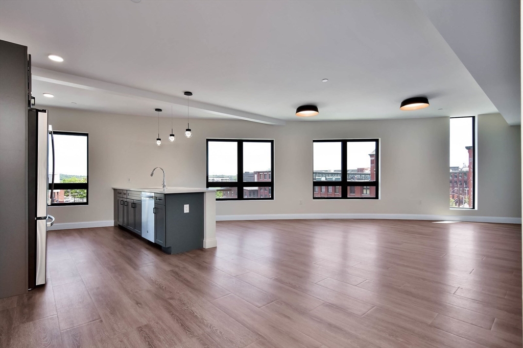 215 Canal Street, Unit 1 Lawrence, MA 01840 - Photo 1 of 6 an empty room with wooden floor and windows