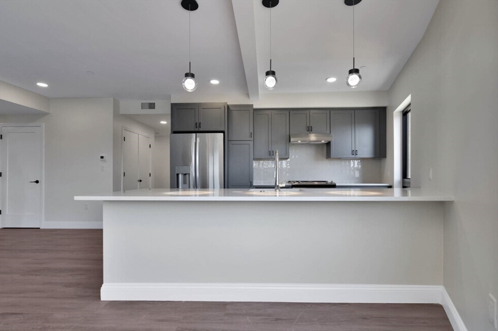 215 Canal Street, Unit 1 Lawrence, MA 01840 - Photo 2 of 6 a large kitchen with stainless steel appliances a large counter top a sink and a stove