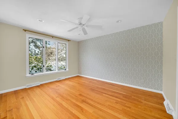 a view of an empty room with a window and wooden floor