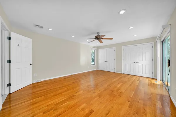 a view of empty room with wooden floor and ceiling fan