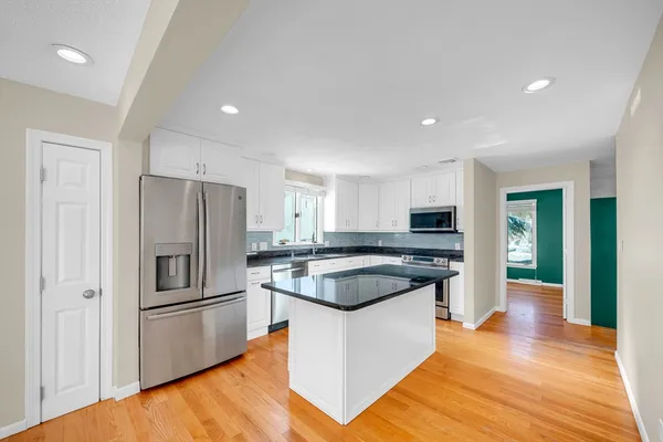 a kitchen with a sink a refrigerator and a stove top oven with wooden floor