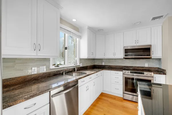 a kitchen with stainless steel appliances white cabinets and a sink