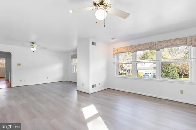a view of an empty room with a window and wooden floor