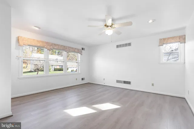 an empty room with windows and fan