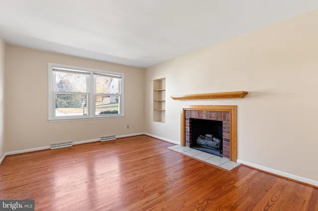 an empty room with wooden floor and fireplace