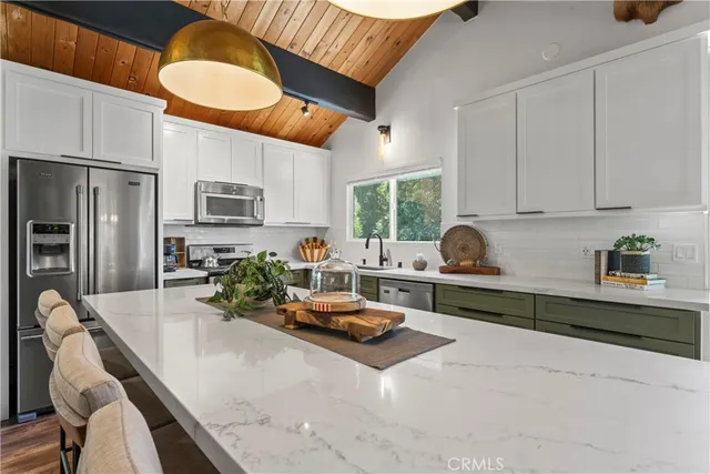 a kitchen with stainless steel appliances kitchen island granite countertop a stove a sink and a refrigerator