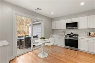 a kitchen with a kitchen island hardwood floor sink stove dining table and chairs