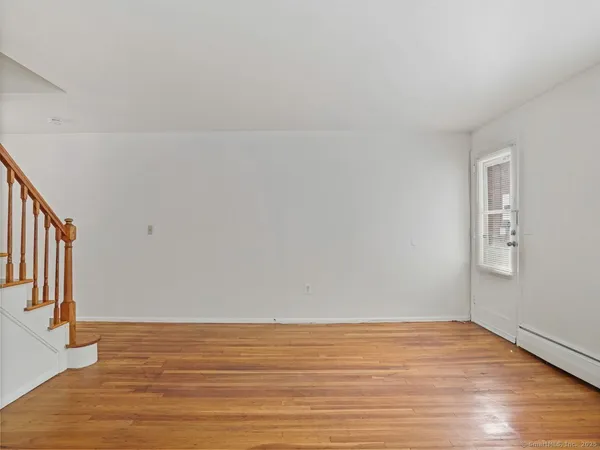 a view of an empty room with wooden floor and stairs