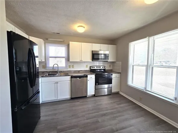 a kitchen with granite countertop a refrigerator stove and microwave