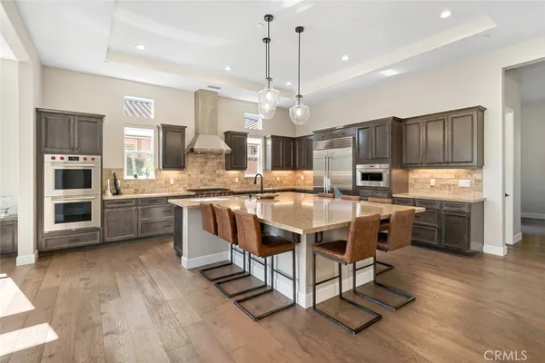 a kitchen with stainless steel appliances granite countertop a stove a sink dishwasher a refrigerator and a oven with wooden floor