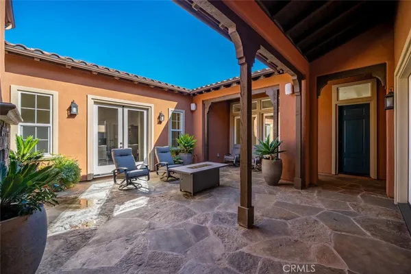 a view of a patio with table and chairs potted plants and floor to ceiling window