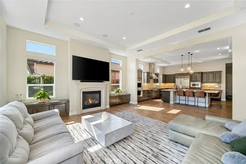 a living room with furniture a fireplace a flat screen tv and windows