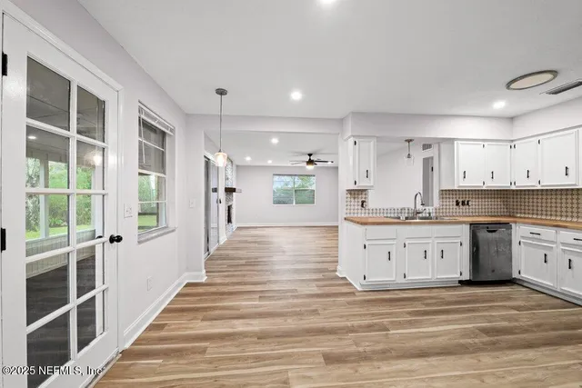 a large white kitchen with granite countertop a large window and white stainless steel appliances