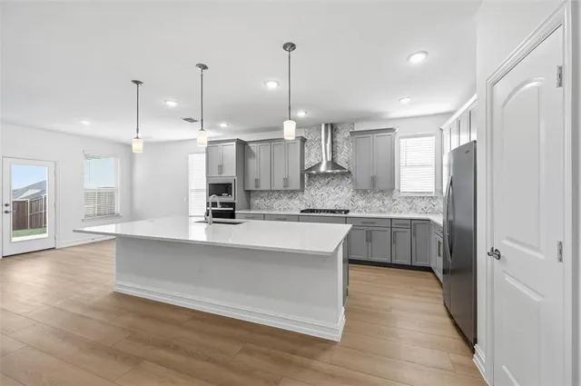 a kitchen with stainless steel appliances granite countertop a sink a stove a refrigerator and white cabinets with wooden floor