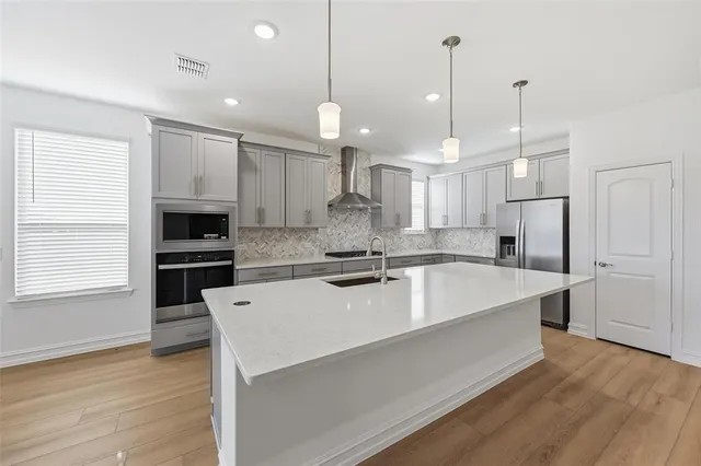 a large kitchen with kitchen island a stove a sink a center island and wooden floor