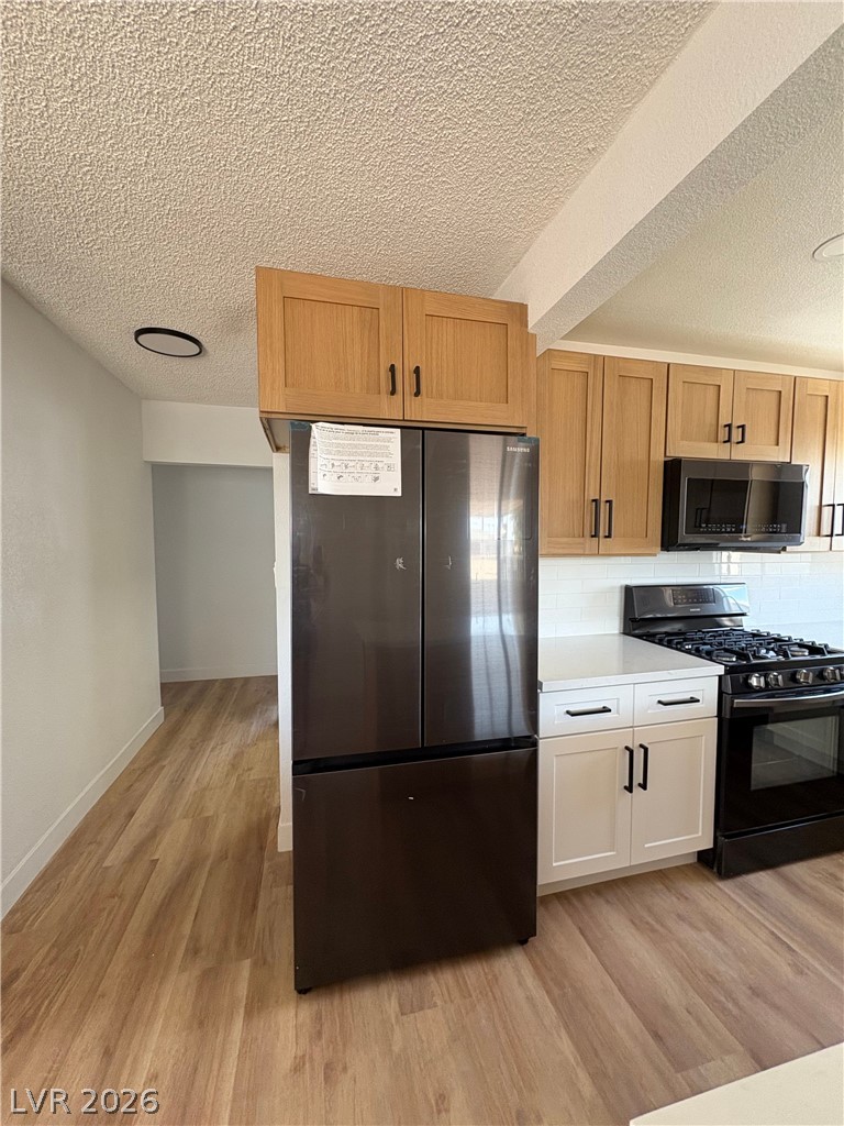 148 Fir Street Henderson, NV 89015 - Photo 4 of 12 Sleek modern cabinetry and durable wood flooring elevate this functional kitchen space.