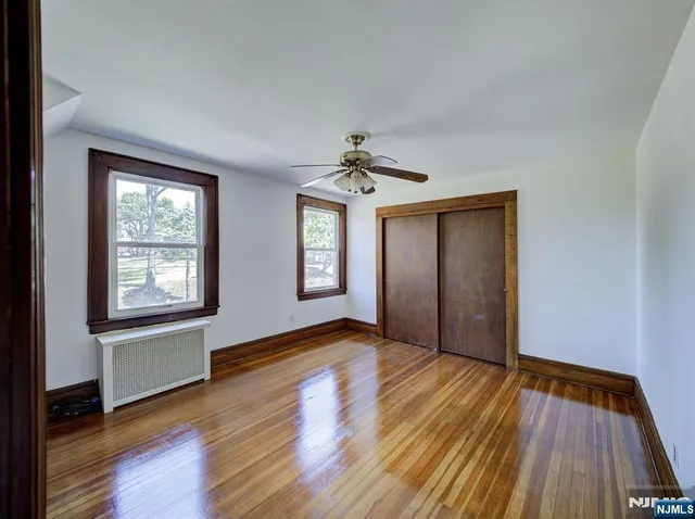 an empty room with wooden floor closet and windows