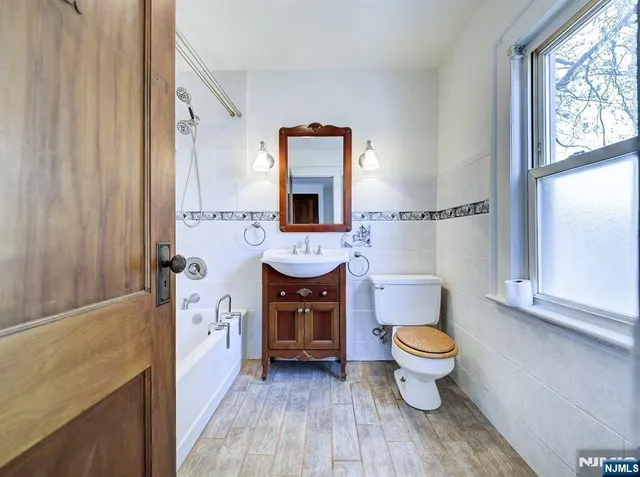 a bathroom with a toilet sink a mirror and window