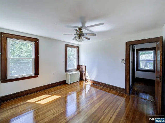 a view of an empty room with window and wooden floor