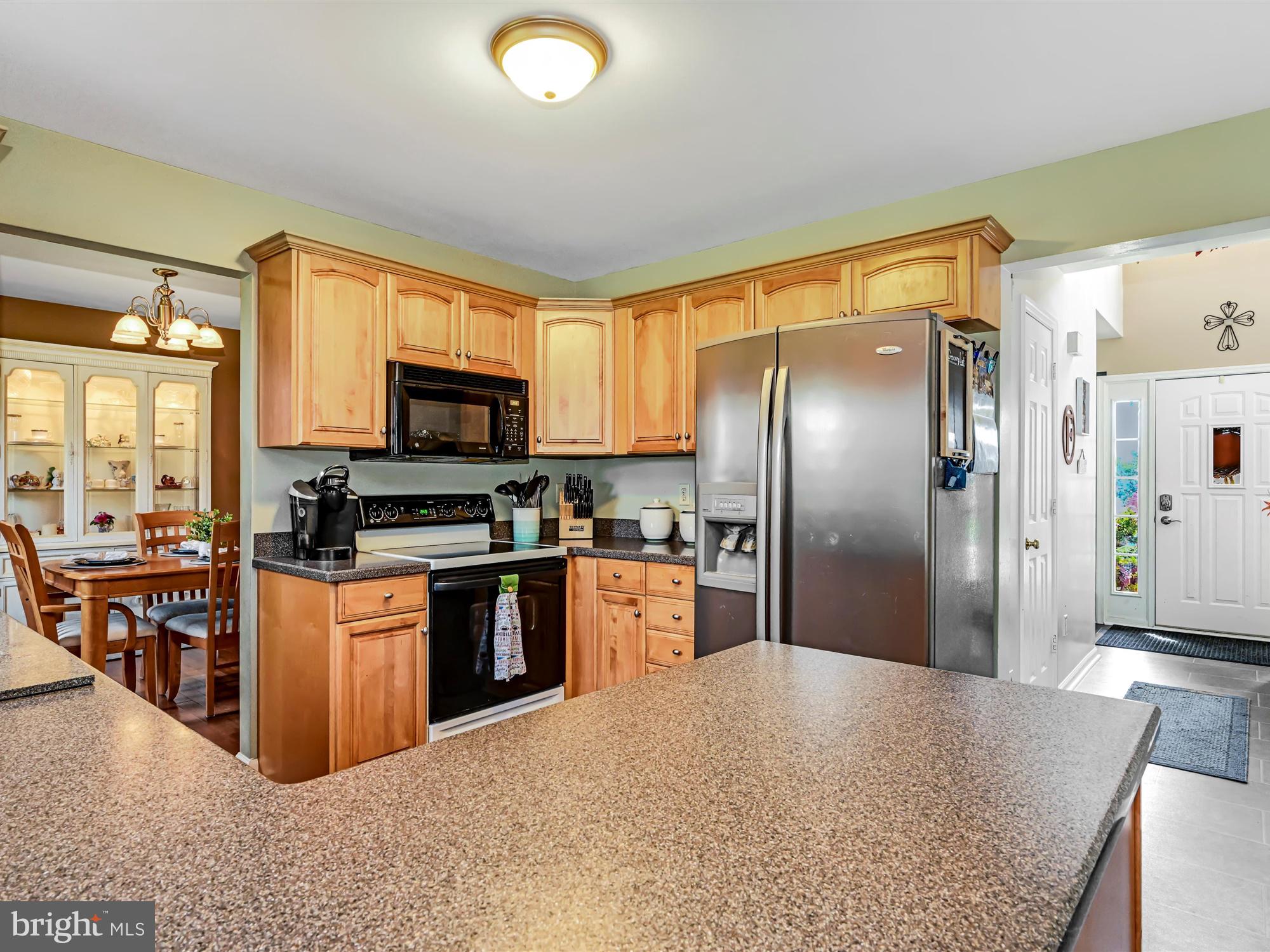 205 Village Spring Lane Reinholds, PA 17569 - Photo 10 of 29 a kitchen with stainless steel appliances granite countertop a refrigerator a stove top oven a sink dishwasher a dining table and chairs with wooden floor