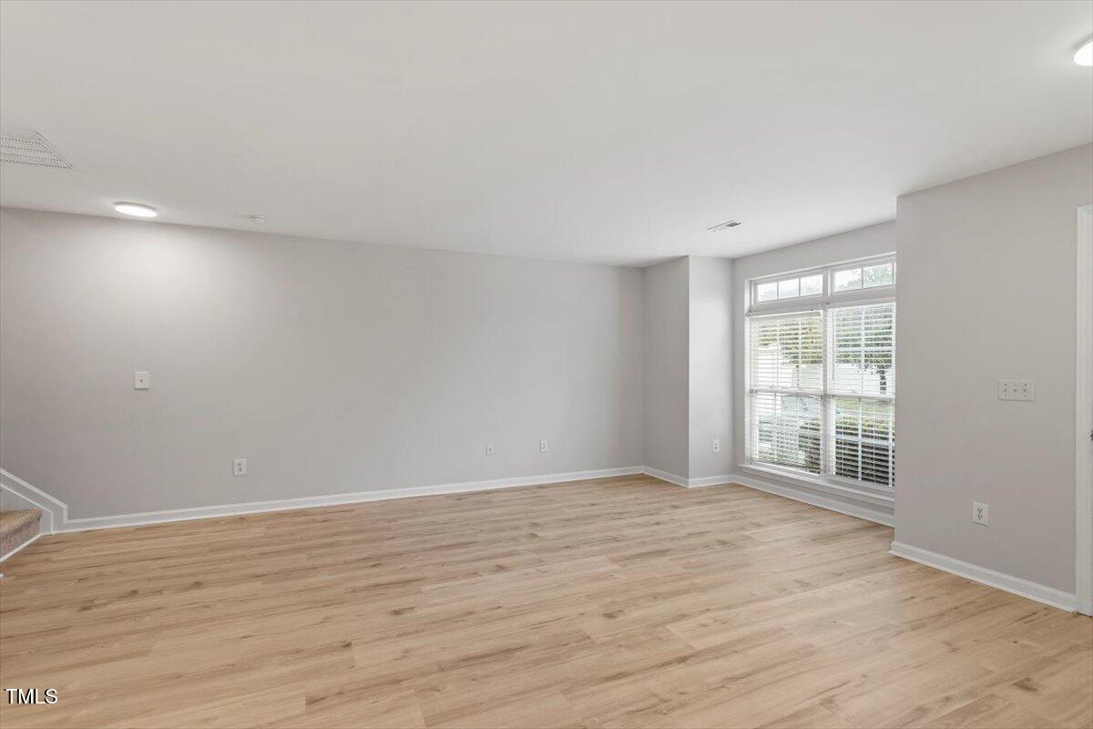 8600 Neuse Landing Lane, Unit 106 Raleigh, NC 27616 - Photo 3 of 22 a view of an empty room with wooden floor and a window