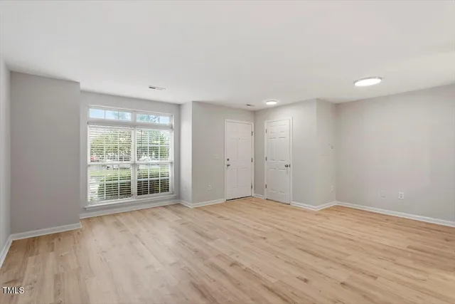 a view of an empty room with wooden floor and a window