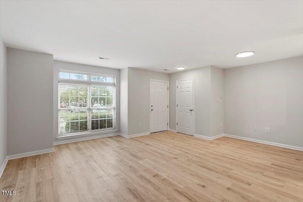 8600 Neuse Landing Lane, Unit 106 Raleigh, NC 27616 - Photo 4 of 22 a view of an empty room with wooden floor and a window