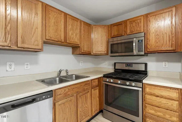 a kitchen with granite countertop wood cabinets stainless steel appliances and a window