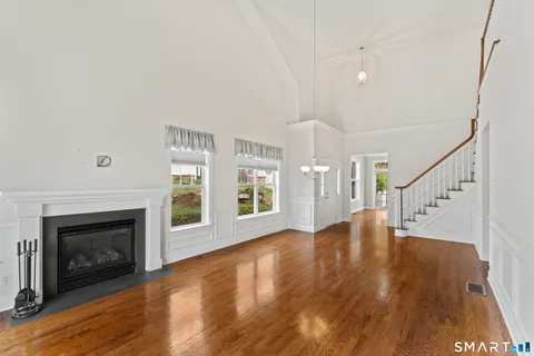 a view of an empty room with wooden floor fireplace and a window