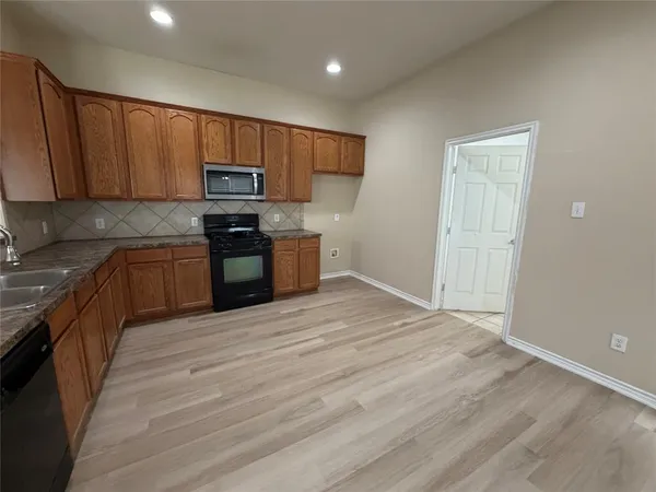 a kitchen with granite countertop wooden cabinets a stove top oven and stainless steel appliances