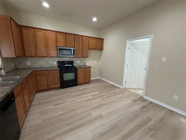 a kitchen with granite countertop wooden cabinets a stove top oven and stainless steel appliances