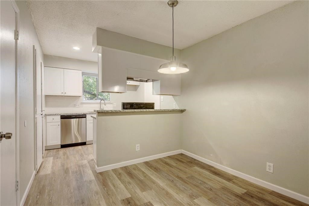 2311 Teri Road, Unit B Austin, TX 78744 - Photo 7 of 25 a kitchen with kitchen island a sink dishwasher a stove and white cabinets with wooden floor