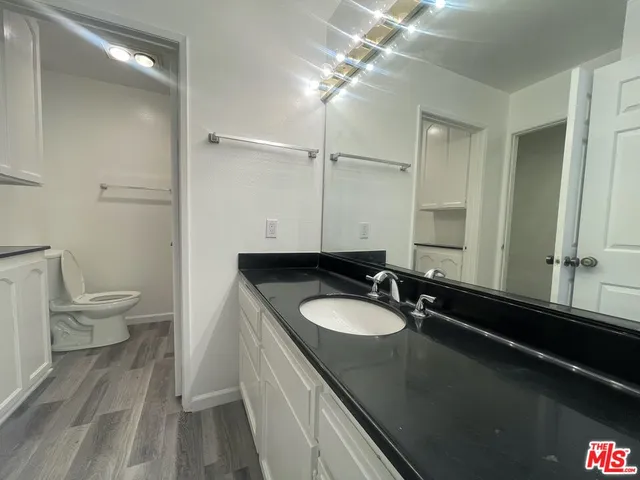 a bathroom with a granite countertop sink a toilet and a mirror