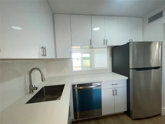 a kitchen with stainless steel appliances a sink a stove a microwave a sink a refrigerator and cabinets