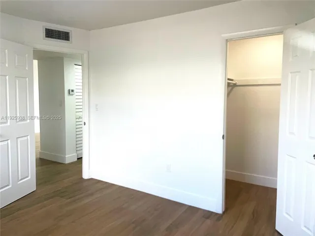 an empty room with wooden floor and closet