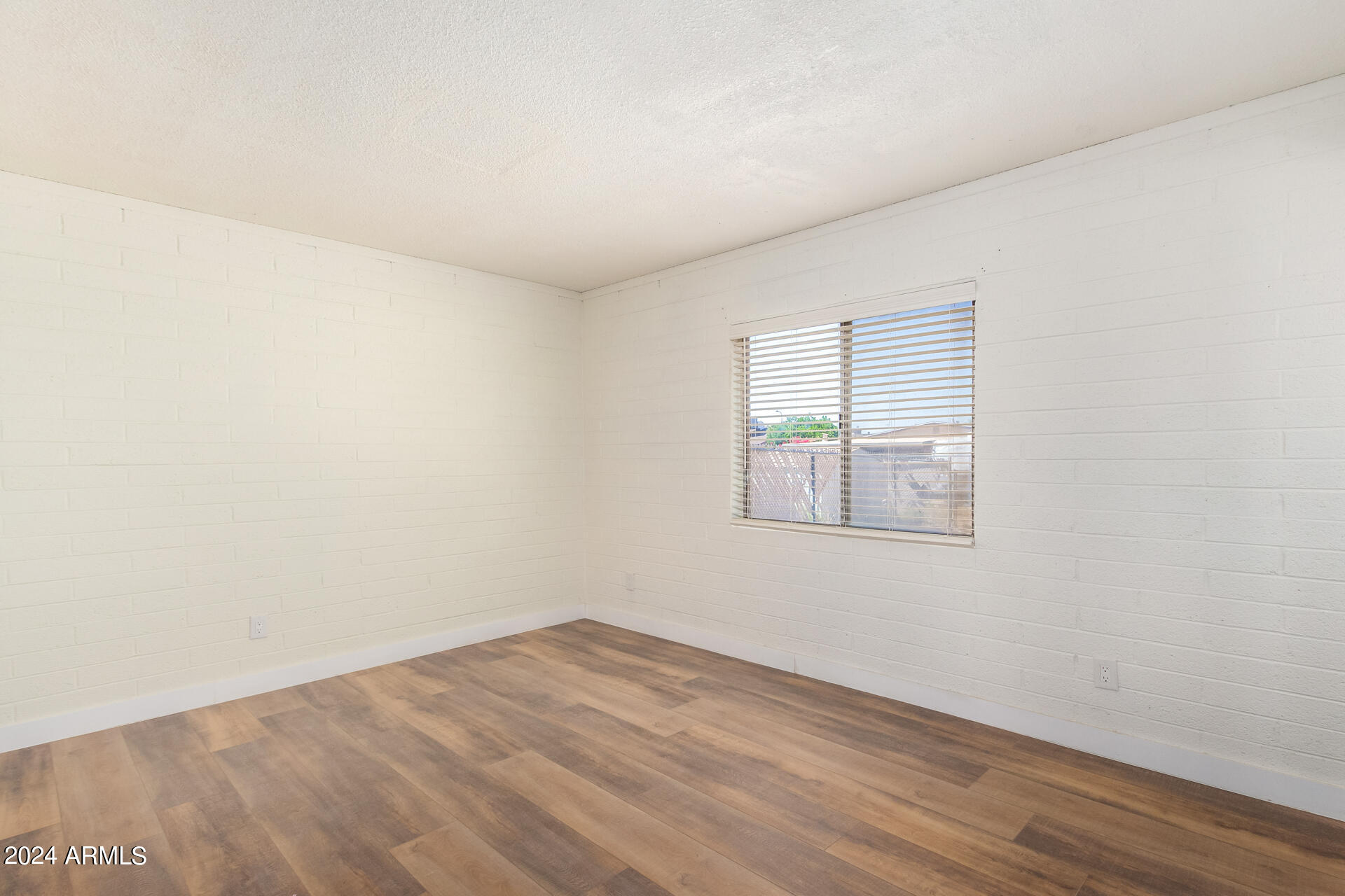 1528 West Maldonado Road Phoenix, AZ 85041 - Photo 14 of 19 an empty room with wooden floor and windows