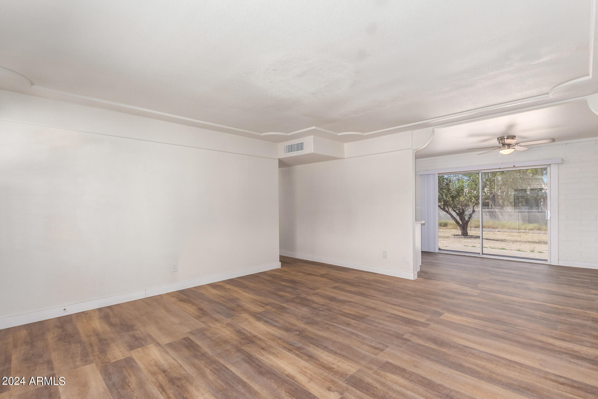 1528 West Maldonado Road Phoenix, AZ 85041 - Photo 5 of 19 a view of an empty room with wooden floor and a window
