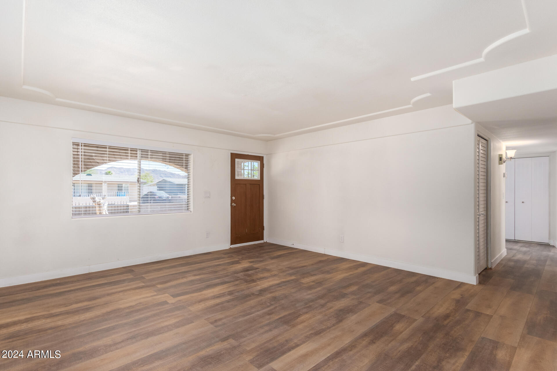 1528 West Maldonado Road Phoenix, AZ 85041 - Photo 6 of 19 an empty room with wooden floor and windows