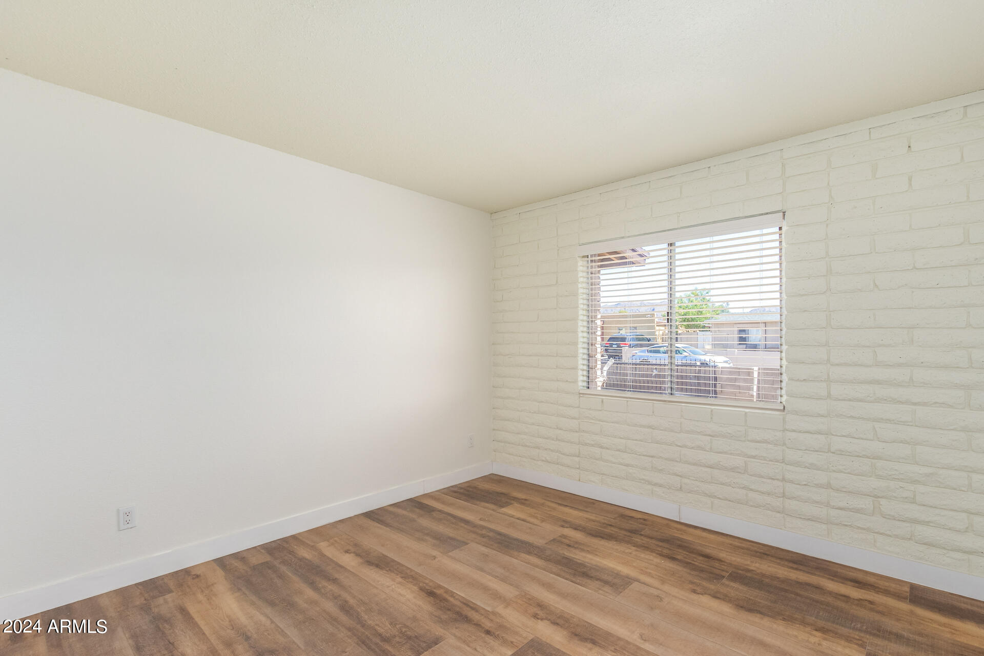 1528 West Maldonado Road Phoenix, AZ 85041 - Photo 9 of 19 an empty room with wooden floor and windows
