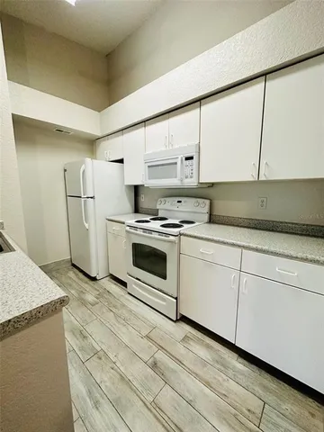 a kitchen with granite countertop white cabinets and white appliances