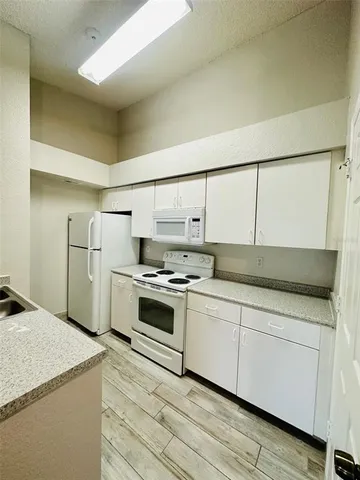 a kitchen with stainless steel appliances a sink dishwasher stove refrigerator and white cabinets with wooden floor
