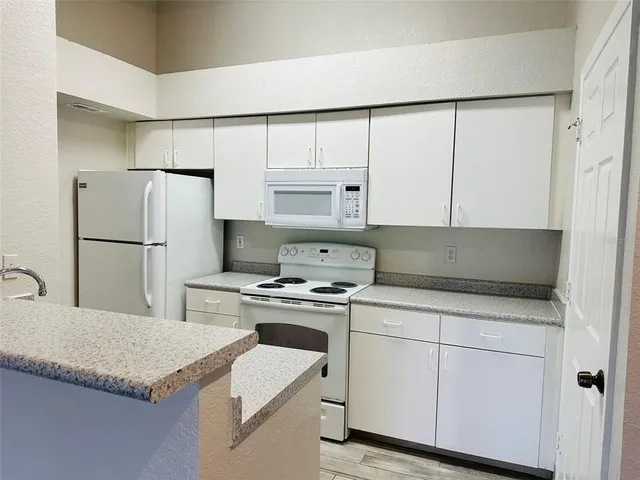 a kitchen with white cabinets and white appliances