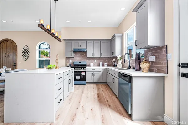 a kitchen with granite countertop a stove a sink a refrigerator and cabinets