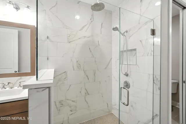 a bathroom with a granite countertop shower a sink and a mirror