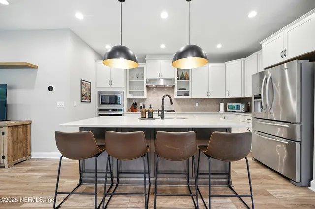 a kitchen with stainless steel appliances granite countertop a sink a stove and a refrigerator with wooden floor