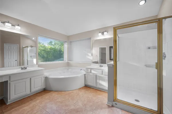 a bathroom with a tub sink shower and mirror