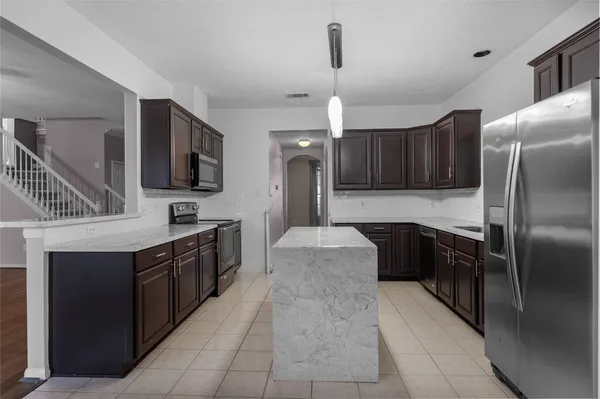 a kitchen with stainless steel appliances granite countertop a refrigerator a sink a stove and oven