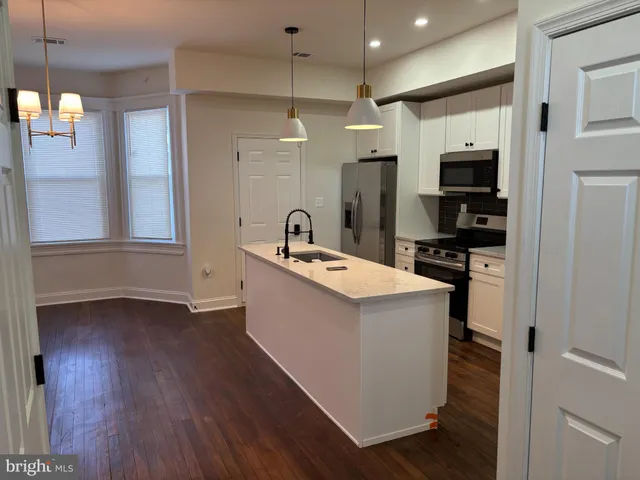 a kitchen with a sink a refrigerator and chairs