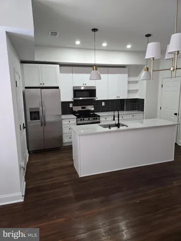 a view of kitchen with stainless steel appliances kitchen island sink stove and refrigerator