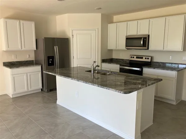 a kitchen with granite countertop a refrigerator a stove and a sink